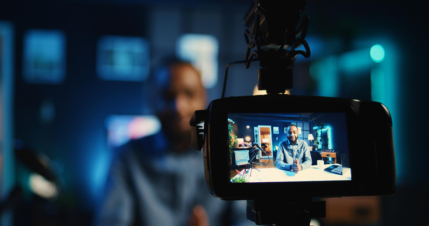 Business videographer recording brand video in studio, focused on camera screen